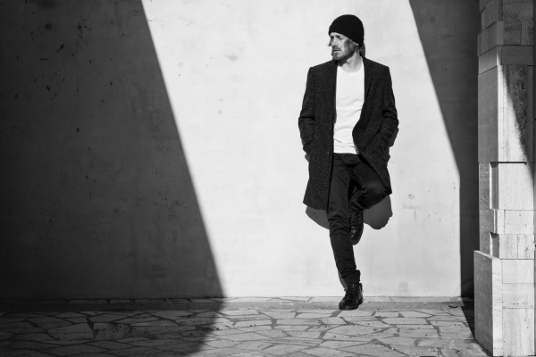 Premium photographer example: Young man leaning against a wall in black and white